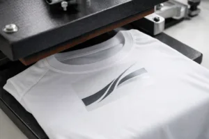 A professional heat press applies a heat transfer label for an itch-free solution on a white sport t-shirt, emphasizing seamless branding integration in manufacturing.