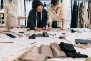 An editorial-style image showing early brand planning with fabrics, sketches, and product direction materials spread across a workspace.