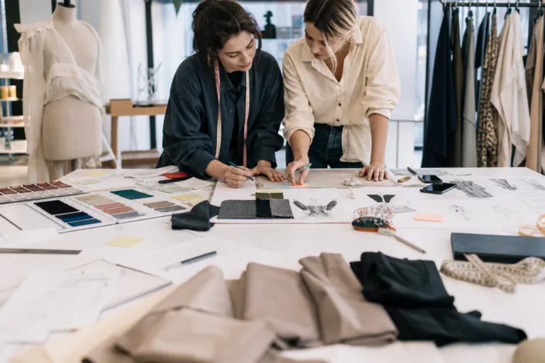 An editorial-style image showing early brand planning with fabrics, sketches, and product direction materials spread across a workspace.