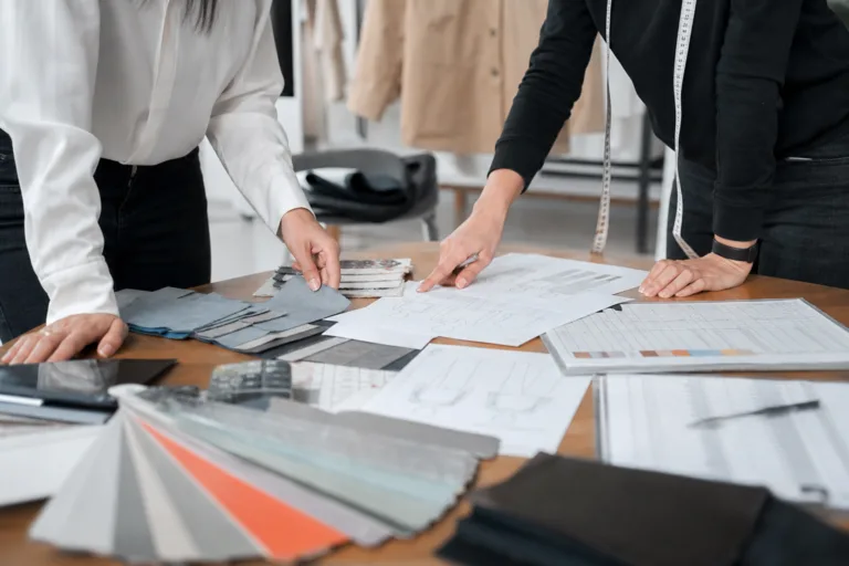 An editorial-style sourcing desk scene showing the practical factors behind apparel minimum order quantities.